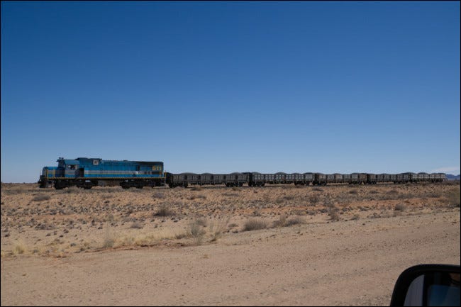 Un tren con el espejo retrovisor de un coche en primer plano. 