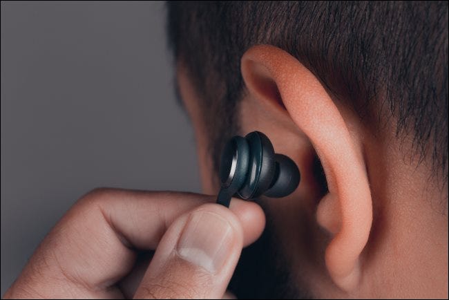 Un hombre se inserta un auricular en la oreja.