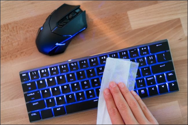Una mano limpiando un teclado separado.