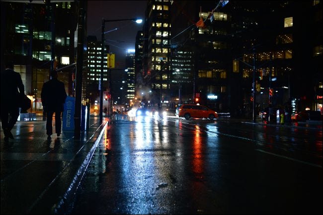 Gente caminando por las calles de Toronto por la noche bajo la lluvia