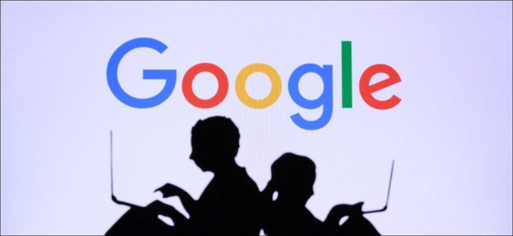 Siluetas de dos personas que usan computadoras portátiles frente a un logotipo de Google