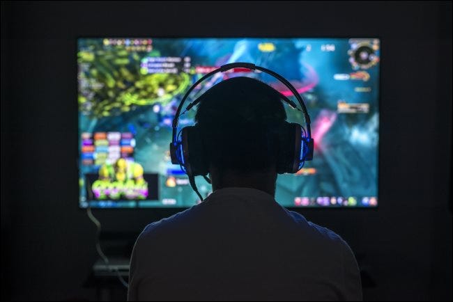 Un joven jugador que juega un juego de PC mientras usa audífonos.
