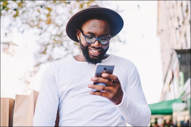Una persona sonriente mirando un teléfono inteligente.