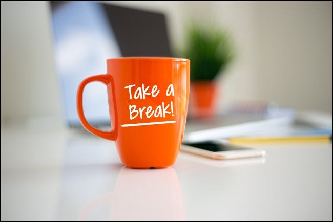 Una taza de café naranja con '¡Tomar un descanso!' impreso en ella.