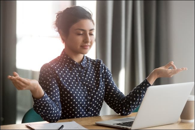 Una mujer meditando frente a un MacBook en una oficina.