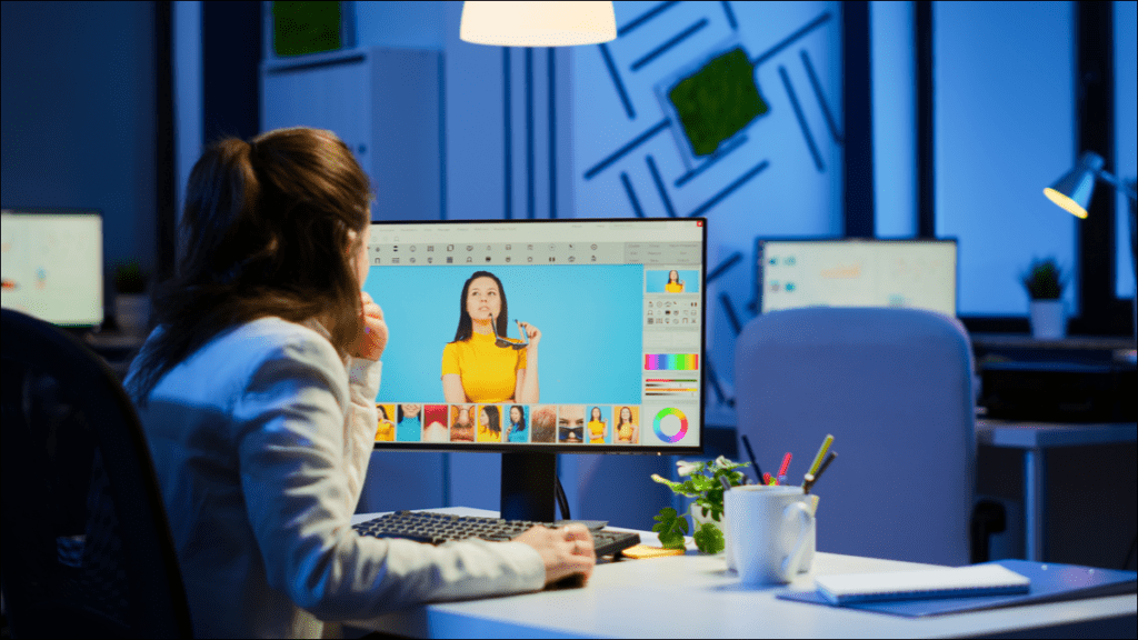 Una mujer viendo y editando fotografías en una computadora de escritorio con Windows.