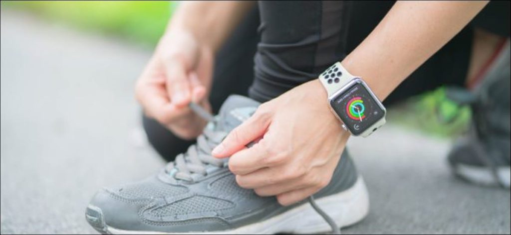 Una mujer atando sus cordones mientras usa un Apple Watch.