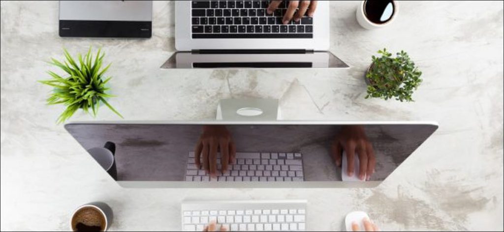 Las manos de una persona que usa una Mac mientras las manos de otra persona que usa una MacBook Pro sobre la mesa.