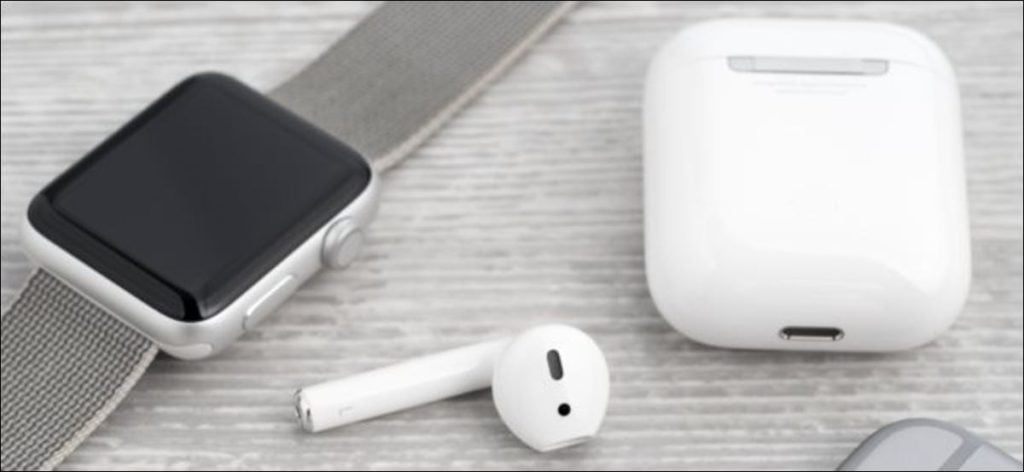 AirPods y su estuche de carga junto a un Apple Watch.