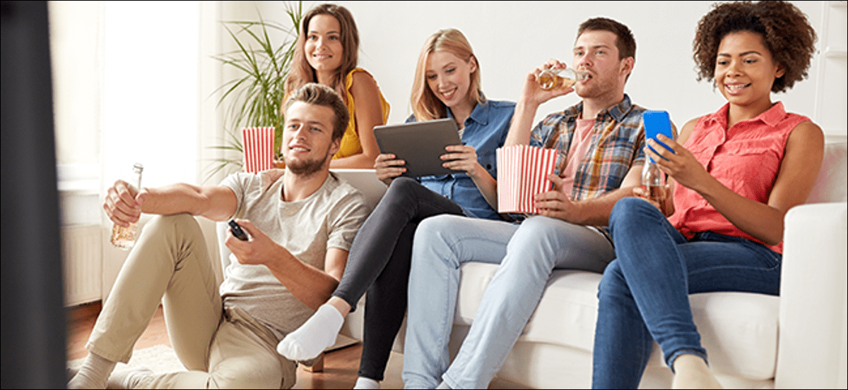 Un grupo de amigos comiendo palomitas de maíz y viendo la televisión.