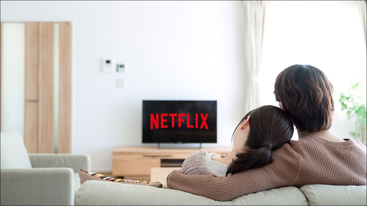 Pareja sentada en el sofá viendo Netflix en la televisión