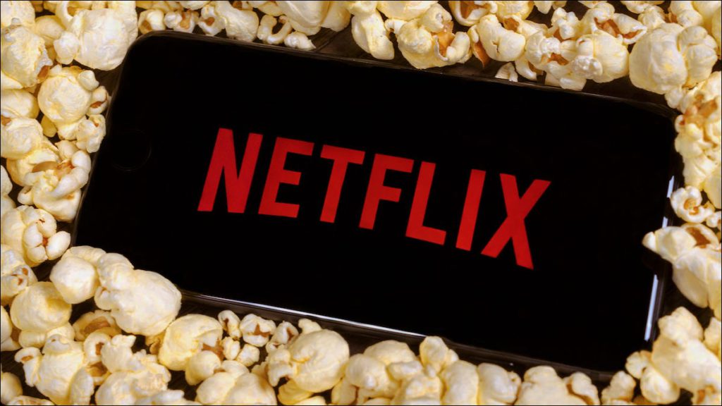 El logotipo de Netflix en un teléfono inteligente que descansa sobre una pila de palomitas de maíz