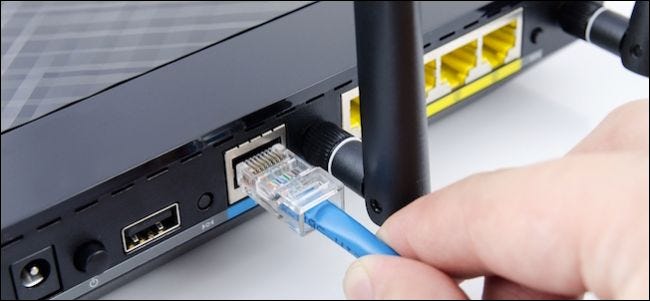 Persona que conecta un cable ethernet a un enrutador