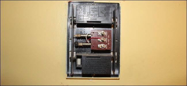 Una caja de timbre con el cableado expuesto, un cable rojo en el terminal trans y blanco en el terminal frontal.