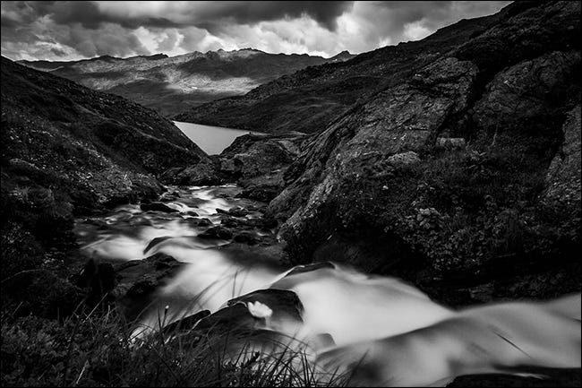 Una foto en blanco y negro de un arroyo en las montañas después de la lluvia.
