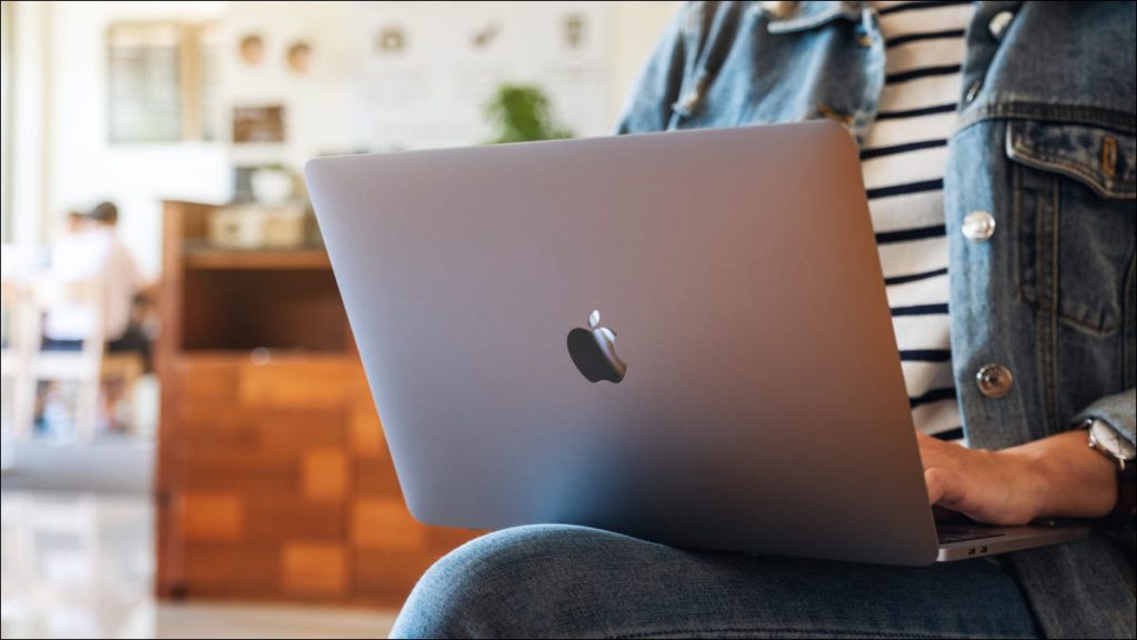 Persona que usa un MacBook de rodillas en un café