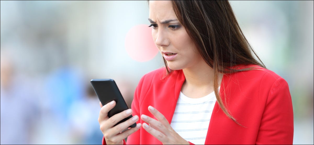 Una mujer preocupada mirando su teléfono inteligente.