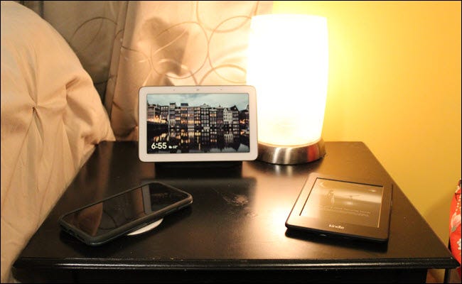 Nest Hub, Kindle y iPhone en una mesita de noche.