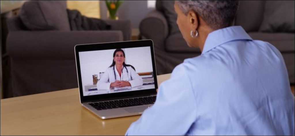 Mujer de edad hablando con el médico en la computadora portátil