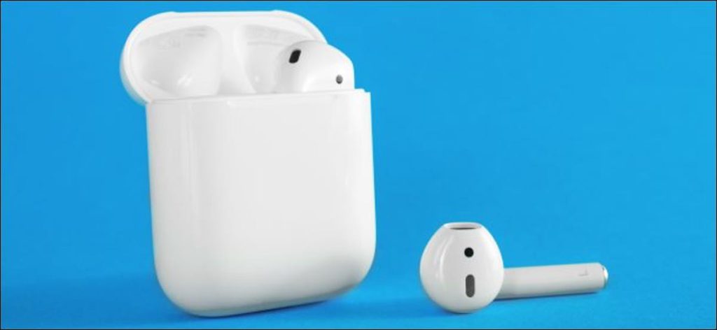 Un Apple AirPod en el estuche de carga y el otro al lado.