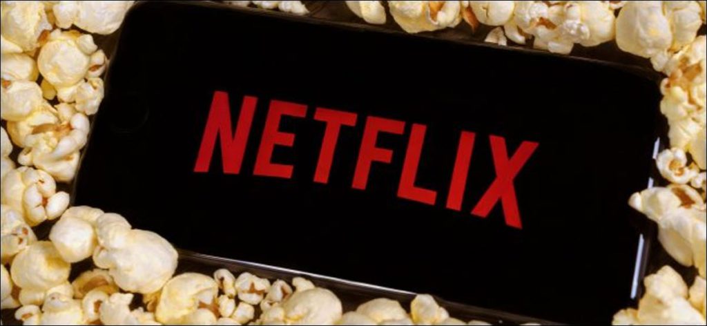 Un teléfono inteligente sobre una pila de palomitas de maíz con el logotipo de Netflix.