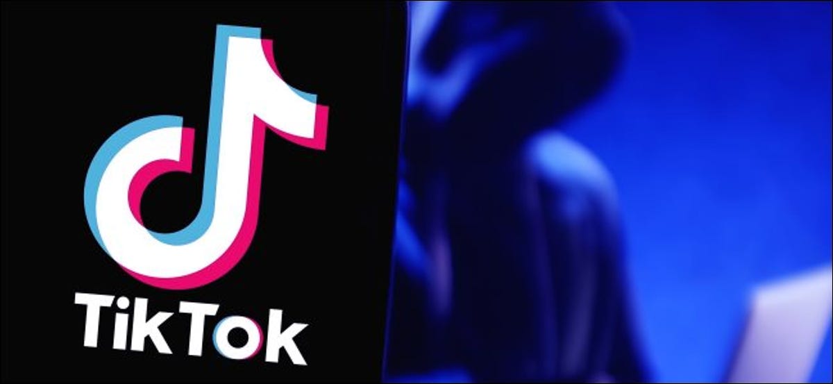 Un logotipo de TikTok en un teléfono con una figura que usa una computadora portátil en el fondo.