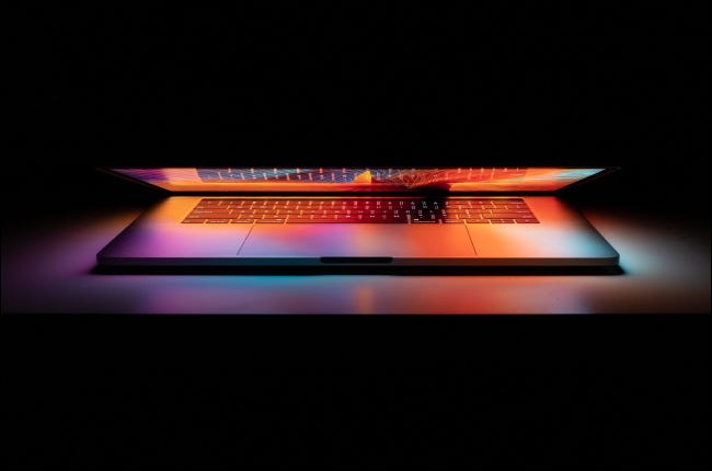 Una MacBook Pro de Apple parcialmente cerrada que brilla en la oscuridad.