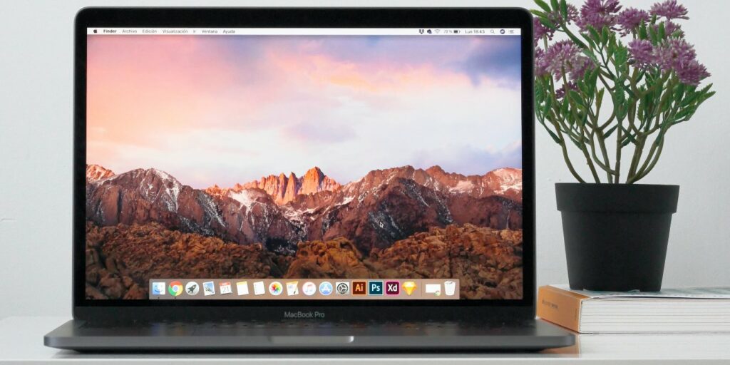 Photo of a MacBook on a desk next to a flower