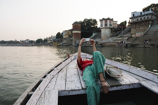Mujer occidental acostada en un barco tomando selfies en Varanasi