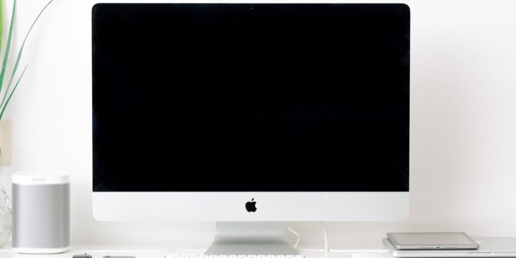 Photo of a Mac perched on a desk next to a plant