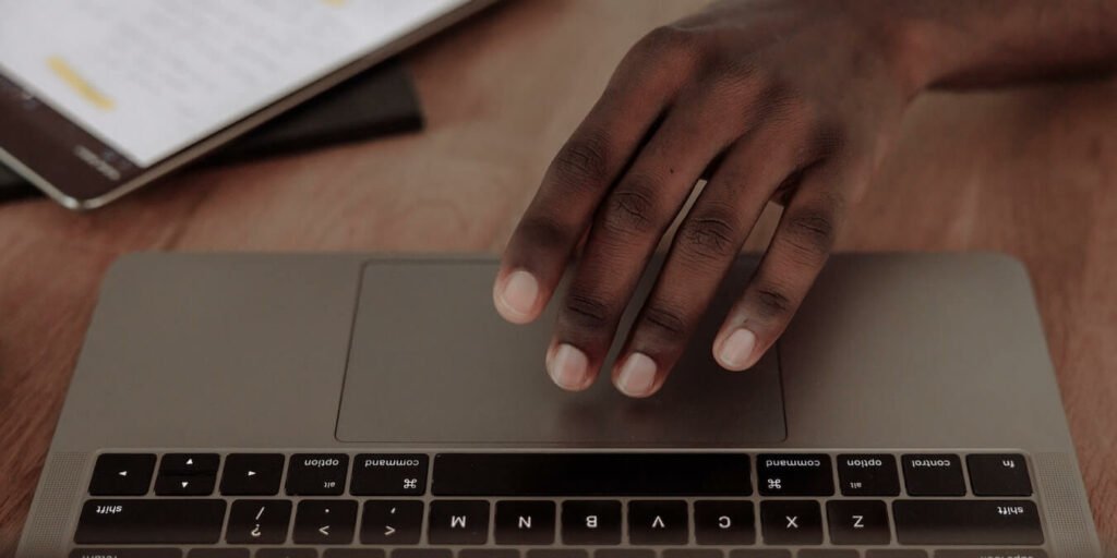 A hand reaching for a MacBook.