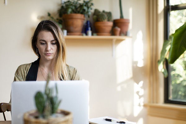 Mujer relajada trabajando desde casa en su computadora portátil