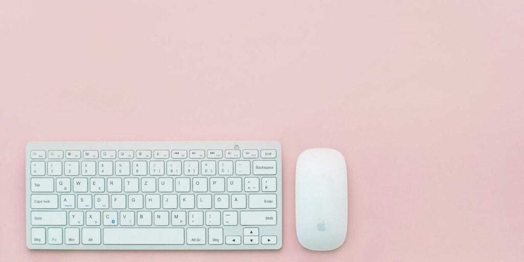 A Mac Keyboard and mouse on a minimalist background.