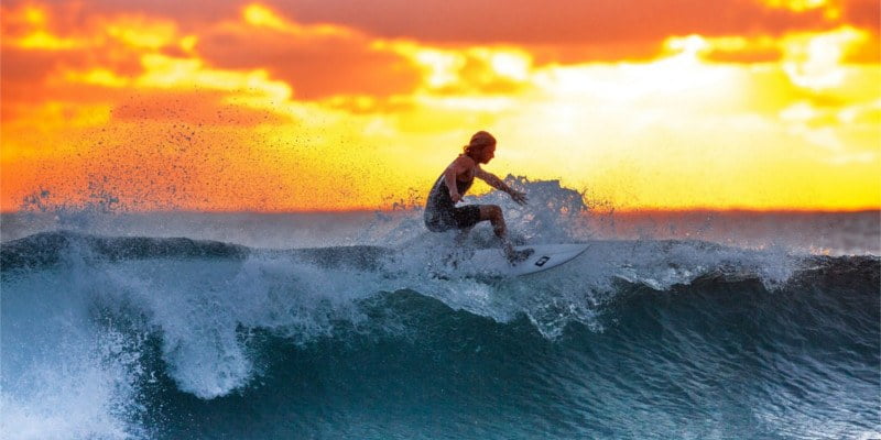 Surfer on wave at dawn